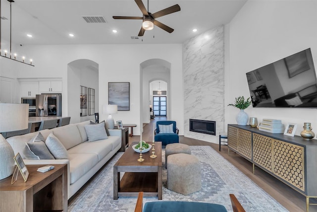 6826 Mirabeau Ln, Katy, TX 77493 - living room featuring arched walkways, a ceiling fan, recessed lighting, wood finished floors, and a high end fireplace
