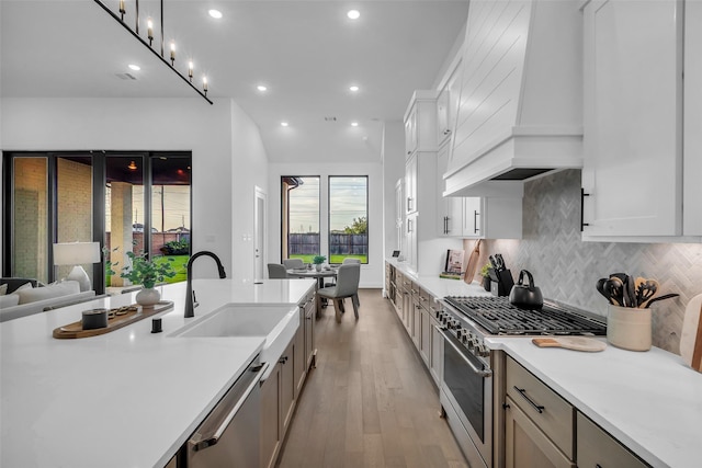 6826 Mirabeau Ln, Katy, TX 77493 - kitchen with stainless steel appliances, wall chimney exhaust hood, light countertops, decorative backsplash, and light wood-type flooring