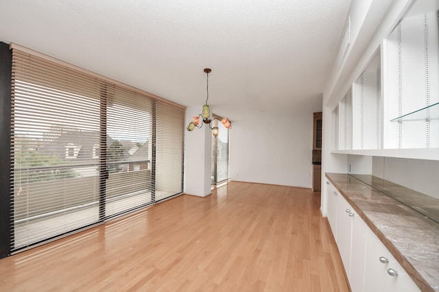 1111 Bering Dr Unit 306, Houston, TX 77057 - unfurnished dining area featuring light wood-type flooring and a chandelier