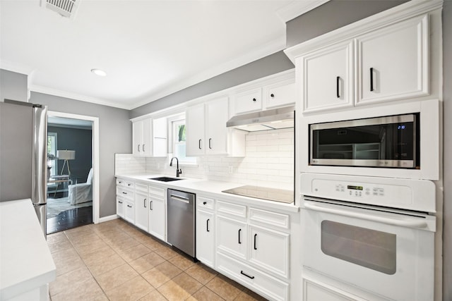 10610 Bordley Dr, Houston, TX 77042 - kitchen with appliances with stainless steel finishes, under cabinet range hood, decorative backsplash, light countertops, and ornamental molding
