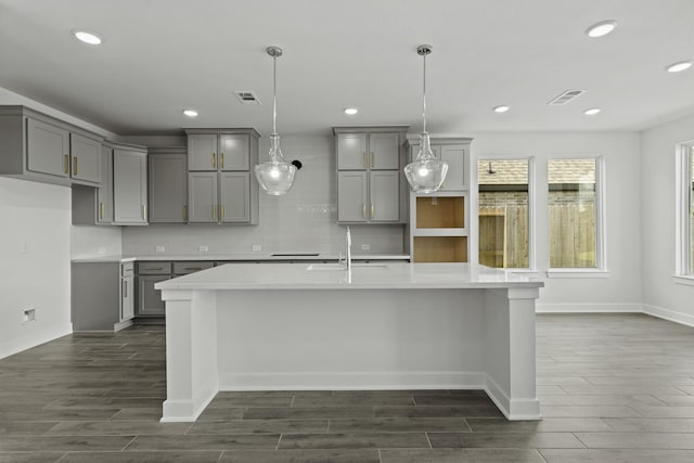 5029 Steady Breeze Dr, Katy, TX 77493 - kitchen featuring gray cabinets, dark wood finished floors, a large island with sink, backsplash, and recessed lighting
