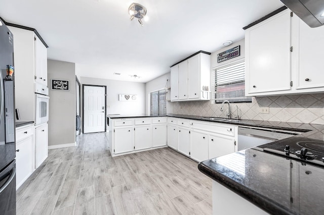 12710 Ashford Pine Dr, Houston, TX 77082 - kitchen featuring a peninsula, backsplash, white cabinetry, white oven, and light wood-type flooring
