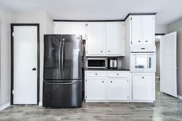 12710 Ashford Pine Dr, Houston, TX 77082 - kitchen with freestanding refrigerator, oven, white cabinetry, dark countertops, and wood finish floors