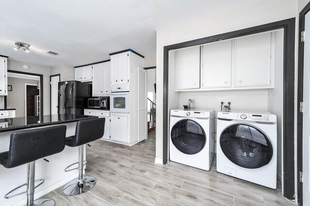12710 Ashford Pine Dr, Houston, TX 77082 - laundry room with washing machine and clothes dryer, cabinet space, and wood finish floors