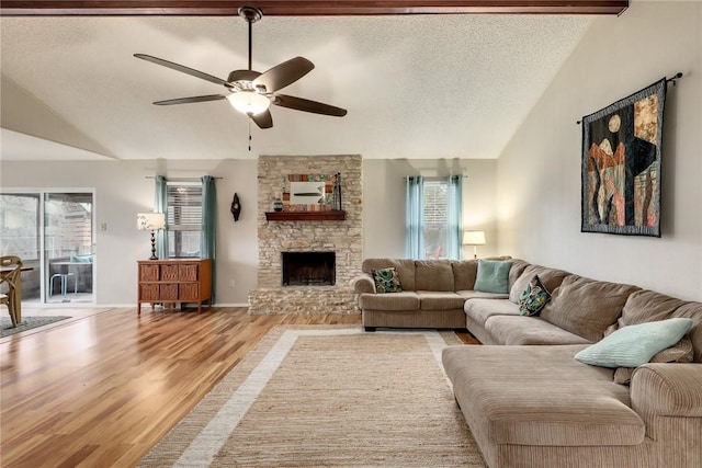 600 Erin Cir, Leander, TX 78641 - living area featuring lofted ceiling, wood finished floors, a stone fireplace, a ceiling fan, and a textured ceiling