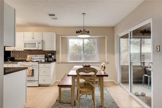 600 Erin Cir, Leander, TX 78641 - kitchen featuring white appliances, dark countertops, light tile patterned floors, white cabinetry, and a textured ceiling