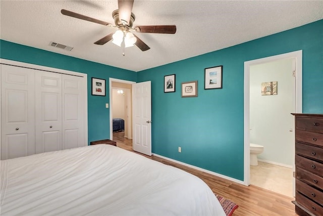 600 Erin Cir, Leander, TX 78641 - bedroom with wood finished floors, a textured ceiling, a closet, ceiling fan, and connected bathroom