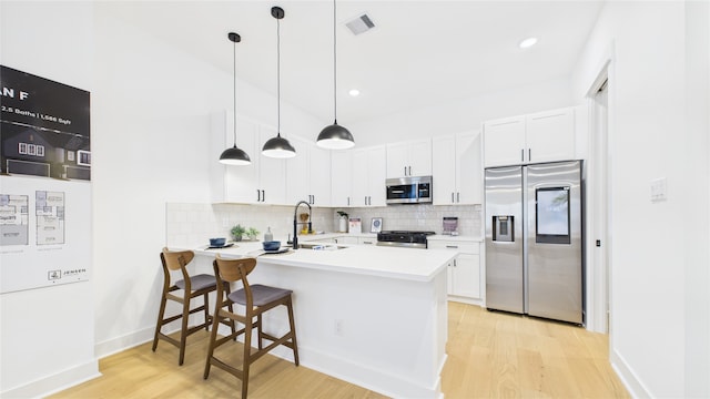 2712 Jensen Creek Ln, Houston, TX 77026 - kitchen featuring appliances with stainless steel finishes, light wood finished floors, a peninsula, tasteful backsplash, and a kitchen breakfast bar