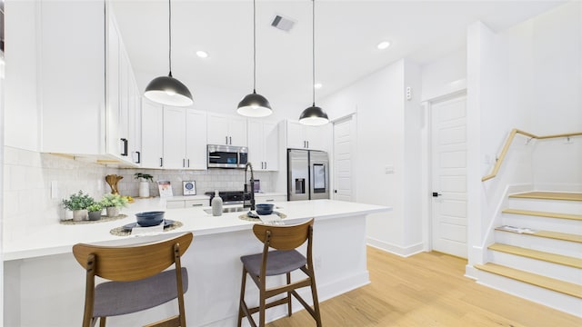 2712 Jensen Creek Ln, Houston, TX 77026 - kitchen featuring stainless steel appliances, tasteful backsplash, a peninsula, light wood-type flooring, and a breakfast bar area