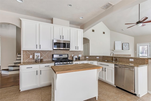 19002 Volley Vale Ct, Humble, TX 77346 - kitchen with stainless steel appliances, arched walkways, wooden counters, tasteful backsplash, and white cabinets