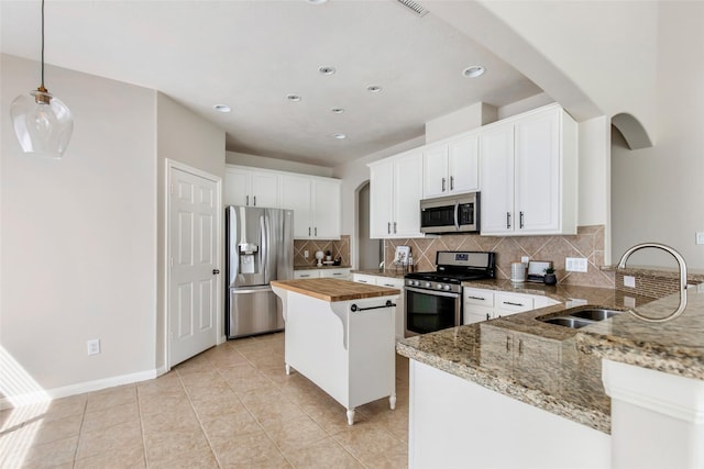19002 Volley Vale Ct, Humble, TX 77346 - kitchen featuring stainless steel appliances, arched walkways, wood counters, tasteful backsplash, and recessed lighting