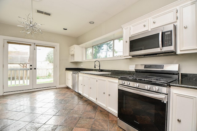 90 Dennis St, Houston, TX 77006 - kitchen featuring stainless steel appliances, white cabinets, stone tile floors, french doors, and recessed lighting