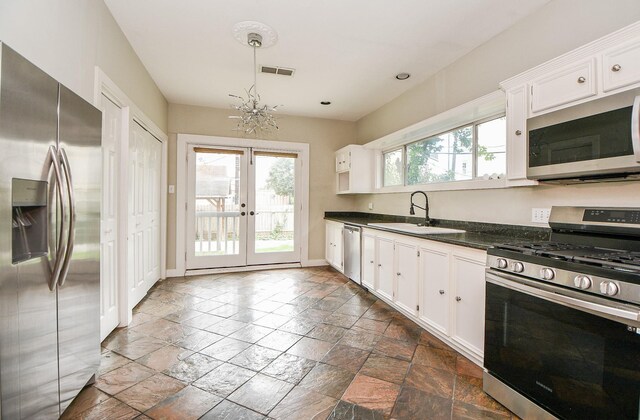 90 Dennis St, Houston, TX 77006 - kitchen featuring appliances with stainless steel finishes, dark countertops, stone tile floors, french doors, and white cabinetry