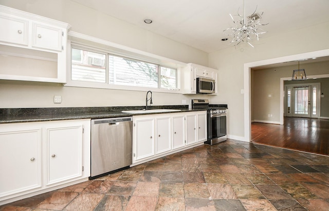 90 Dennis St, Houston, TX 77006 - kitchen featuring stainless steel appliances, stone tile floors, dark countertops, and white cabinetry