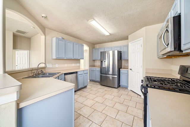3434 Fiorella Way, Humble, TX 77338 - kitchen with appliances with stainless steel finishes, blue cabinets, arched walkways, light countertops, and light tile patterned floors