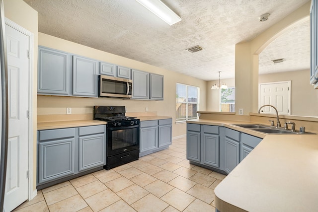 3434 Fiorella Way, Humble, TX 77338 - kitchen featuring stainless steel microwave, black range with gas cooktop, light tile patterned floors, a textured ceiling, and light countertops