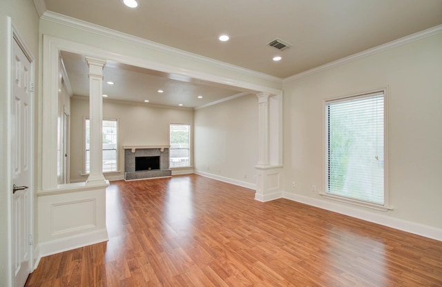 5701 Winsome Ln Unit 2, Houston, TX 77057 - unfurnished living room featuring decorative columns, light wood-type flooring, crown molding, a fireplace with raised hearth, and recessed lighting