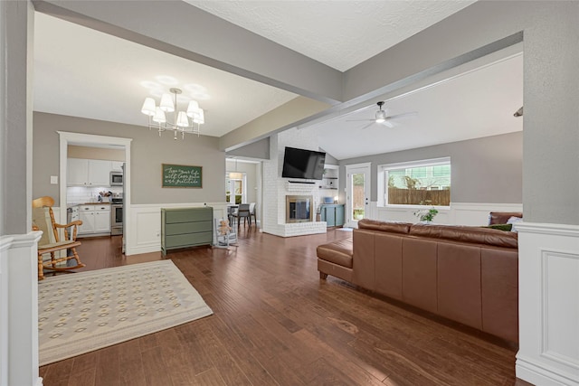 12814 Westmere Dr, Houston, TX 77077 - living room with a fireplace, a ceiling fan, dark wood-style flooring, a chandelier, and a wainscoted wall