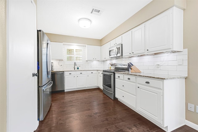 12814 Westmere Dr, Houston, TX 77077 - kitchen with appliances with stainless steel finishes, dark wood finished floors, tasteful backsplash, light stone counters, and white cabinets