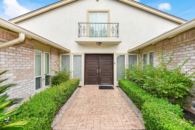 8911 Birdwood Ct, Houston, TX 77096 - view of exterior entry featuring a balcony, brick siding, and stucco siding