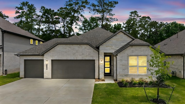 15308 Sandhill Crane Ln, Conroe, TX 77384 - french country style house with an attached garage, driveway, a yard, a shingled roof, and stone siding
