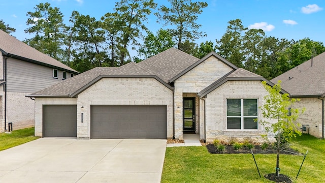 15308 Sandhill Crane Ln, Conroe, TX 77384 - french country inspired facade with an attached garage, driveway, a front yard, and roof with shingles