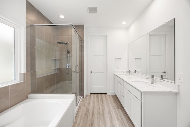 15308 Sandhill Crane Ln, Conroe, TX 77384 - bathroom with a shower stall, double vanity, a bath, wood finished floors, and recessed lighting