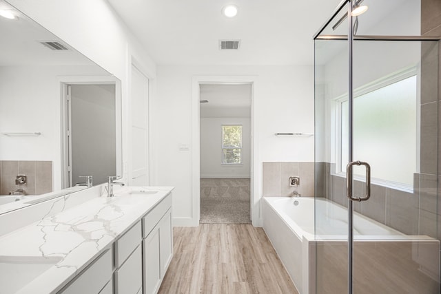 15308 Sandhill Crane Ln, Conroe, TX 77384 - bathroom featuring a bath, wood finished floors, double vanity, a stall shower, and recessed lighting