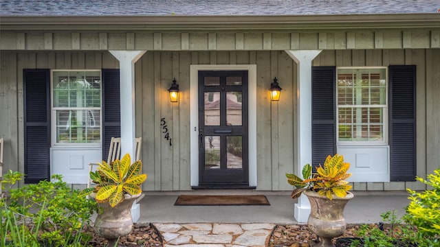 5541 Schumacher Ln, Houston, TX 77056 - doorway to property featuring covered porch, a shingled roof, and board and batten siding