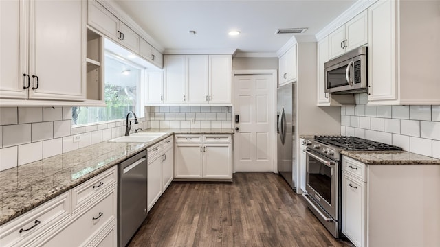 5541 Schumacher Ln, Houston, TX 77056 - kitchen featuring appliances with stainless steel finishes, dark wood-style floors, white cabinetry, tasteful backsplash, and ornamental molding