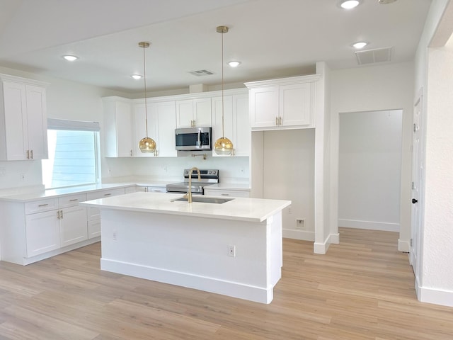 1310 Denson Allen, Coldspring, TX 77331 - kitchen with stainless steel microwave, light countertops, white cabinets, a center island with sink, and light wood-style floors