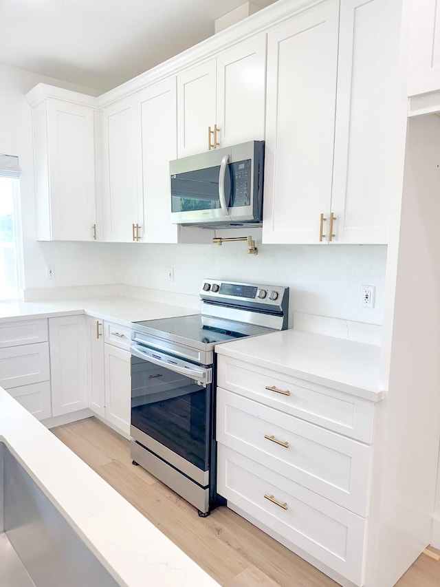1310 Denson Allen, Coldspring, TX 77331 - kitchen with stainless steel appliances, light wood-type flooring, and white cabinetry