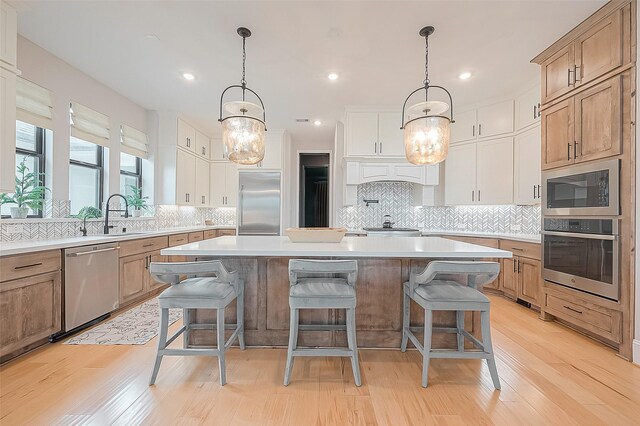 2201 Mulberry Ridge Ct, Manvel, TX 77578 - kitchen featuring built in appliances, a kitchen island, a breakfast bar area, light countertops, and backsplash