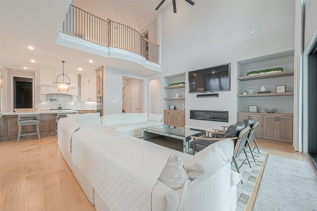 2201 Mulberry Ridge Ct, Manvel, TX 77578 - living area featuring light wood-style floors, built in shelves, a towering ceiling, recessed lighting, and ceiling fan