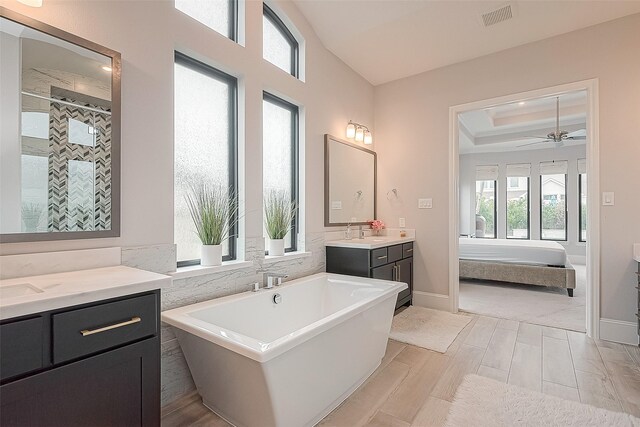 2201 Mulberry Ridge Ct, Manvel, TX 77578 - ensuite bathroom featuring a soaking tub, two vanities, a stall shower, wood finished floors, and a ceiling fan