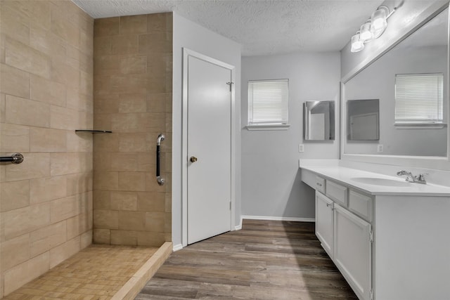 1602 Evesham Dr, Houston, TX 77015 - bathroom featuring vanity, wood finished floors, a textured ceiling, and a tile shower