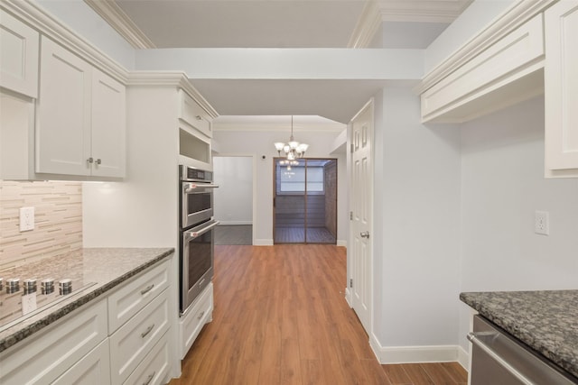 12859 Kingsbridge Ln, Houston, TX 77077 - kitchen featuring appliances with stainless steel finishes, a chandelier, ornamental molding, tasteful backsplash, and light wood-style flooring