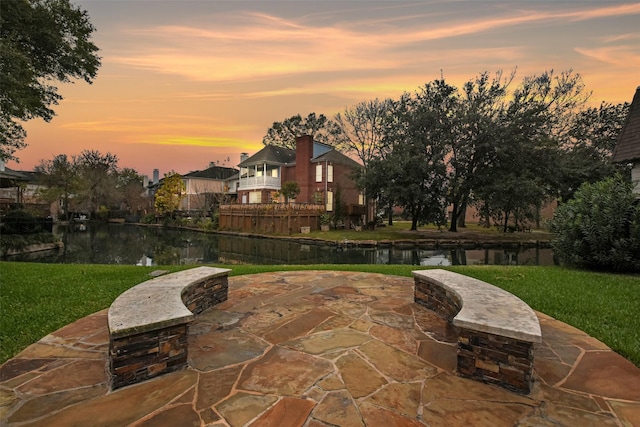 12859 Kingsbridge Ln, Houston, TX 77077 - patio terrace at dusk with a patio area, a lawn, and a water view