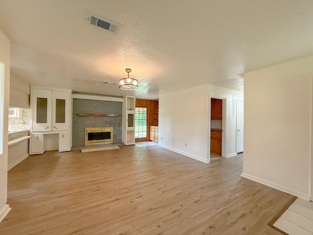 20 Woods Ln, Coldspring, TX 77331 - unfurnished living room featuring light wood finished floors, a brick fireplace, and a chandelier