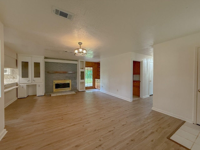 20 Woods Ln, Coldspring, TX 77331 - unfurnished living room featuring a chandelier, a fireplace, and light wood-style flooring