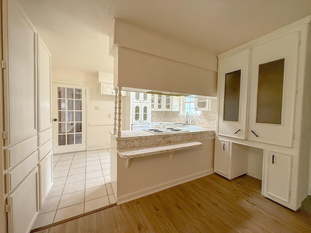20 Woods Ln, Coldspring, TX 77331 - kitchen with glass insert cabinets, a peninsula, white cabinetry, and a kitchen bar