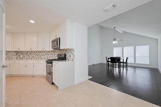 12230 Southmeadow Dr, Stafford, TX 77477 - kitchen featuring appliances with stainless steel finishes, ceiling fan, a textured ceiling, tasteful backsplash, and vaulted ceiling