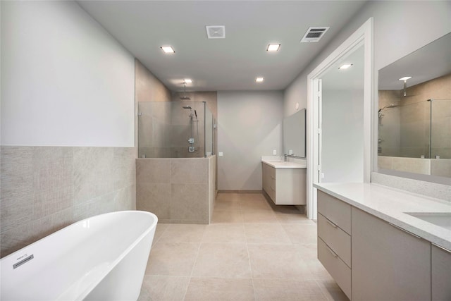1111 W 21st St, Houston, TX 77008 - bathroom with a stall shower, two vanities, tile patterned flooring, a soaking tub, and tile walls