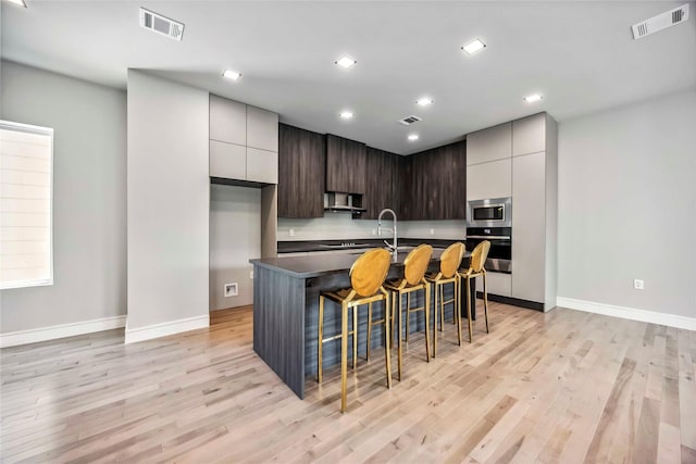 1111 W 21st St, Houston, TX 77008 - kitchen featuring appliances with stainless steel finishes, wall chimney exhaust hood, modern cabinets, light wood-type flooring, and recessed lighting