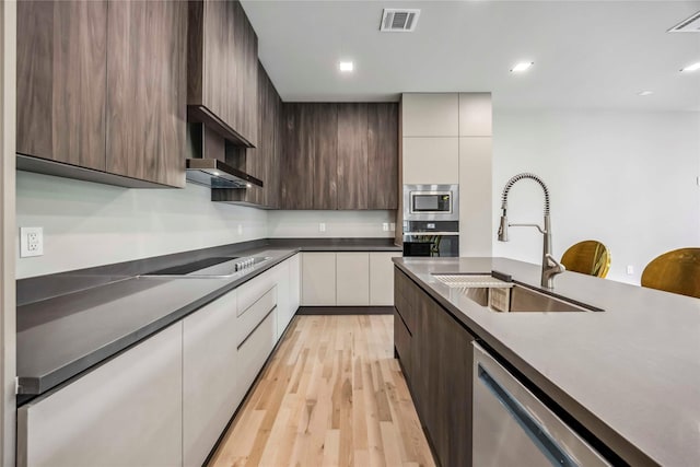 1111 W 21st St, Houston, TX 77008 - kitchen with appliances with stainless steel finishes, modern cabinets, light wood-style floors, dark countertops, and recessed lighting