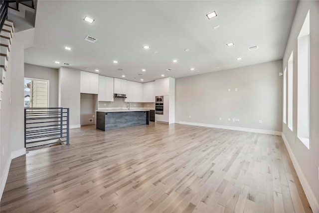 1111 W 21st St, Houston, TX 77008 - unfurnished living room featuring light wood-style flooring, stairway, and recessed lighting