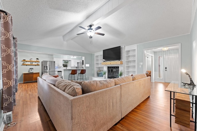 2014 17th St N, Texas City, TX 77590 - living area featuring a ceiling fan, a textured ceiling, light wood-style flooring, a fireplace, and built in shelves
