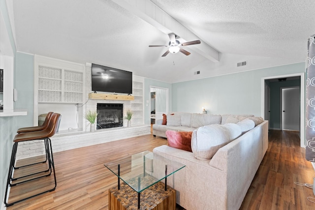 2014 17th St N, Texas City, TX 77590 - living room featuring wood finished floors, a fireplace with raised hearth, a ceiling fan, a textured ceiling, and built in shelves