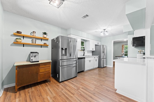2014 17th St N, Texas City, TX 77590 - kitchen with stainless steel appliances, light wood finished floors, white cabinetry, light countertops, and a textured ceiling