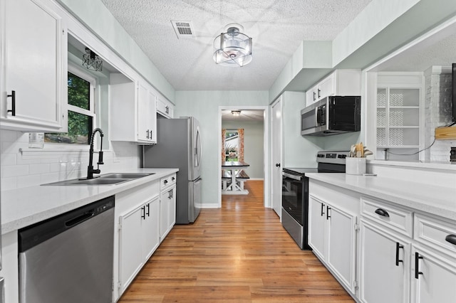 2014 17th St N, Texas City, TX 77590 - kitchen featuring appliances with stainless steel finishes, a textured ceiling, white cabinets, light countertops, and light wood-type flooring